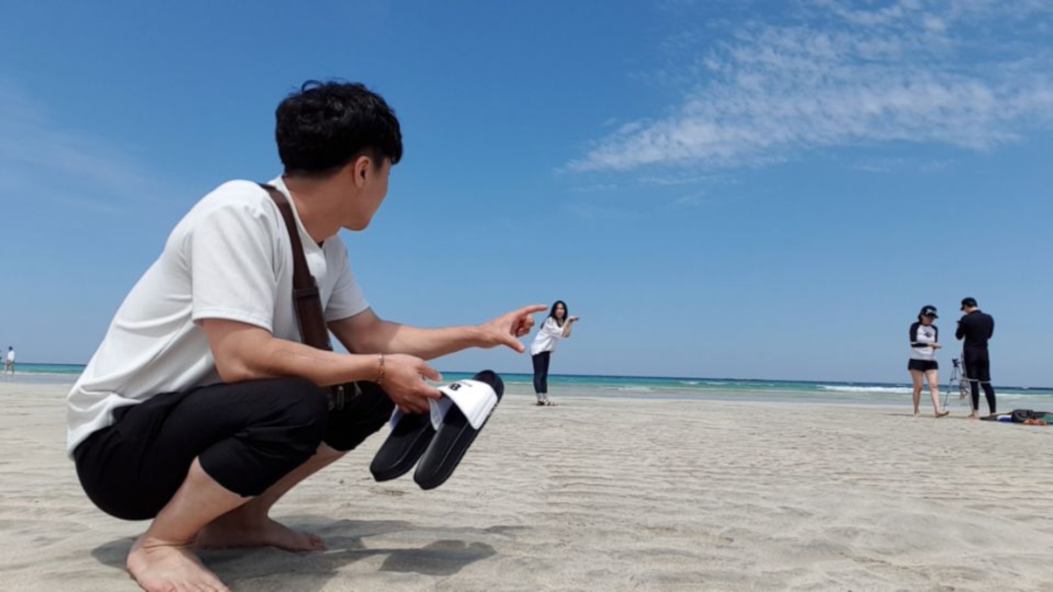 바닷가에서 원근법 장난을 치는 두 사람